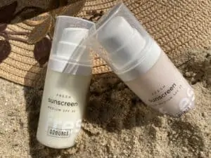 Blogartikel Natürlicher Sonnenschutz - Strohhut mit Sonnencreme im Sand