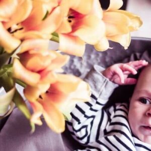 Kleines Baby schaut auf gelbe Lilien - Blogartikel Mein Weg zur Stoffwindelberaterin