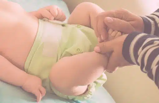 Baby liegt auf dem Wickeltisch und trägt eine hellgrüne Stoffwindel