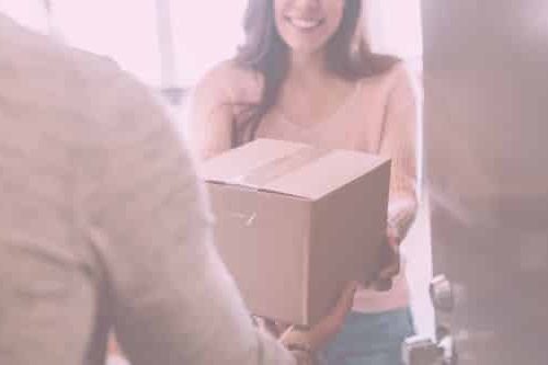Frau nimmt Paket entgegen und lächelt dabei