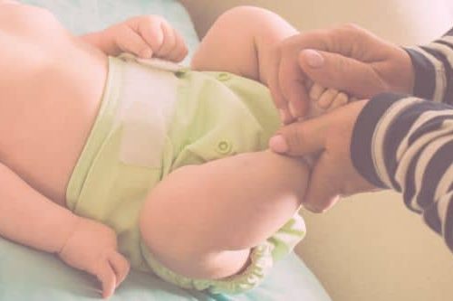 Baby liegt auf dem Wickeltisch und trägt eine hellgrüne Stoffwindel